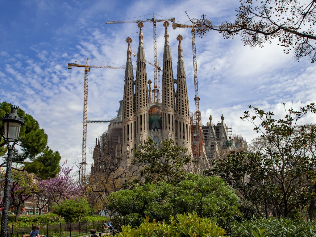 The iconic Sagrada Familia basilica surrounded by greenery, a masterpiece of Gaudí's architecture.